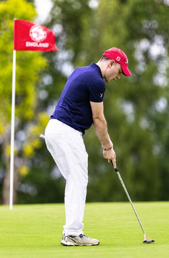 Marco Cioffi jugando al golf, concentrado antes de ejecutar un putt sobre el green.